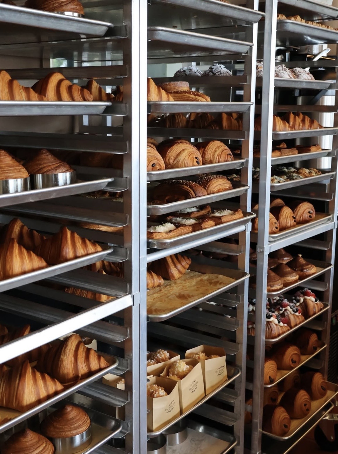 Bakery racks filled with fresh croissants and pastries